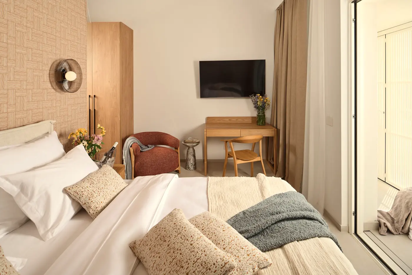 A bedroom in linen and oak with a terracotta armchair