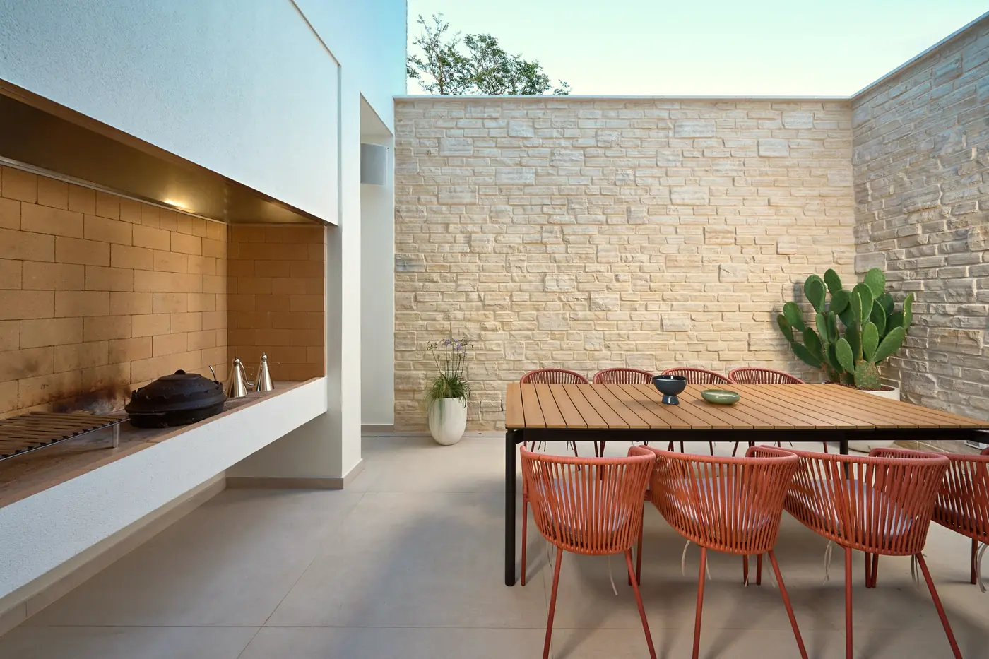 The walled courtyard with a stone barbecue and a long table