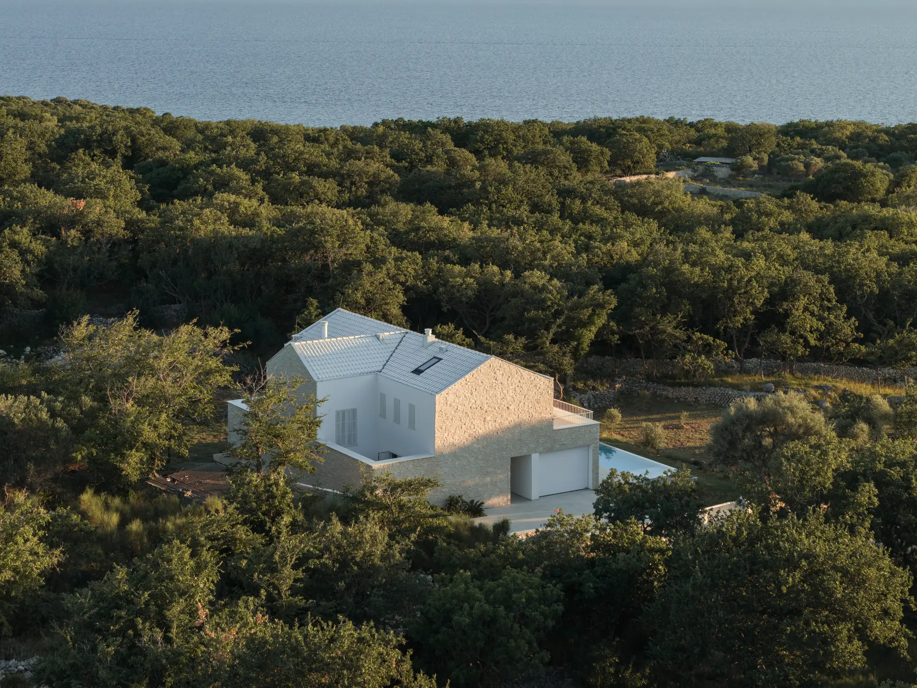 The house from the air, among oak and olive woods, the sea behind