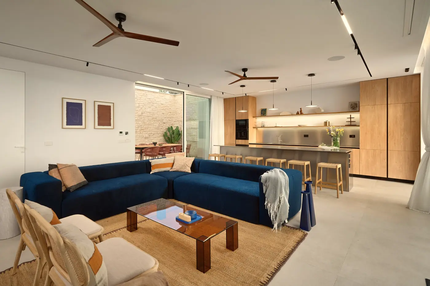 The living room: blue sofa, jute rug and the open kitchen beyond