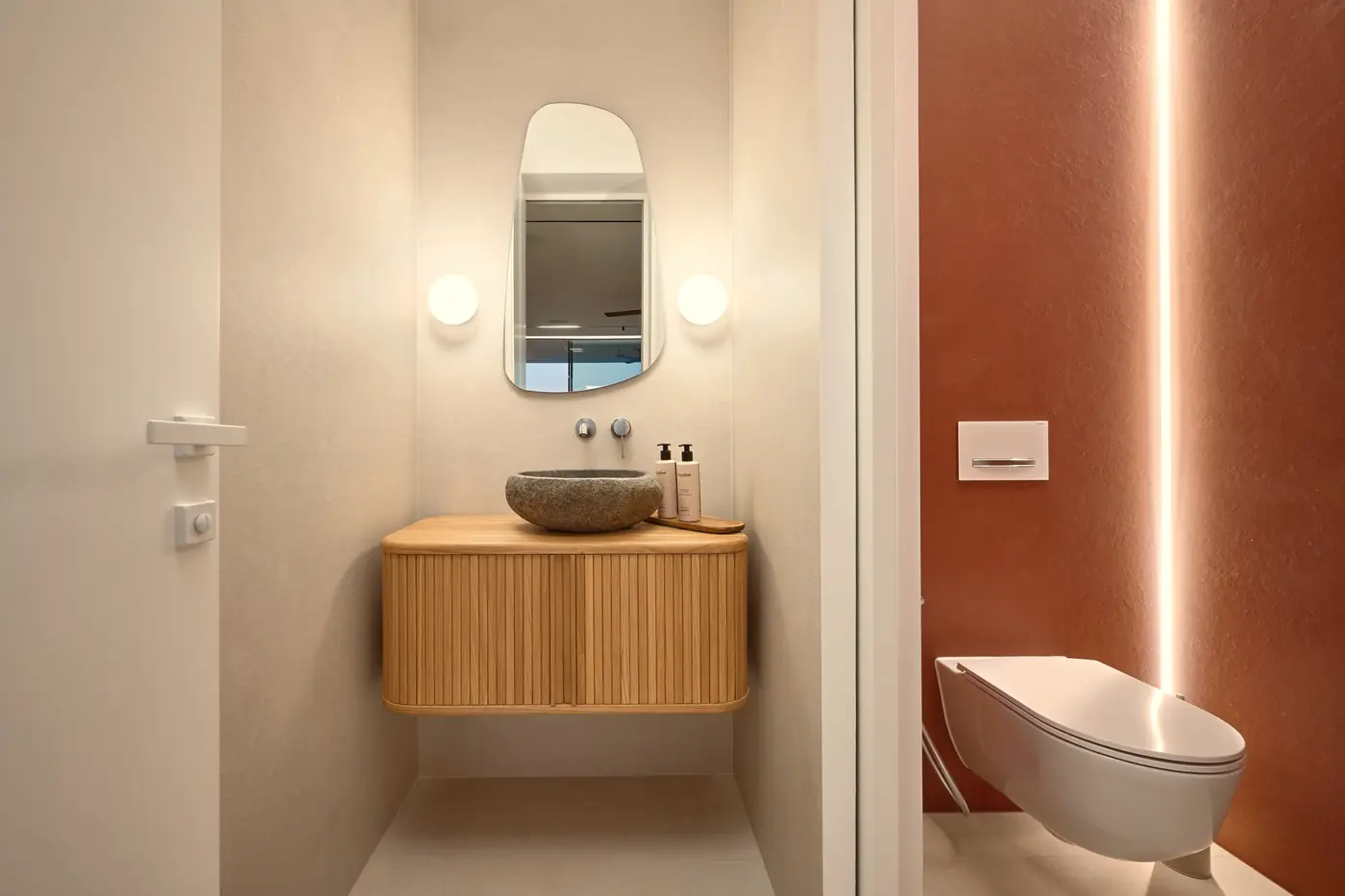 A powder room with an oak vanity and a river-stone basin